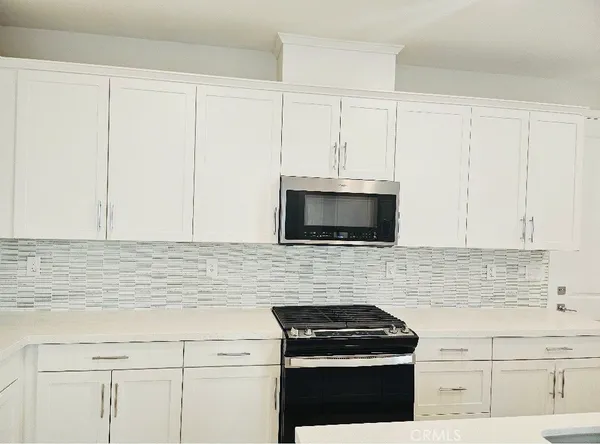 a kitchen with white cabinets and stainless steel appliances