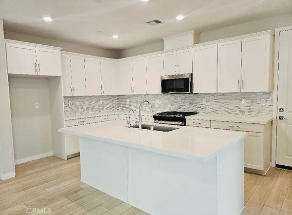 a kitchen with granite countertop white cabinets and stainless steel appliances