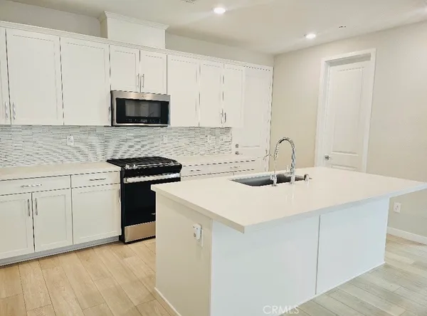 a kitchen with stainless steel appliances granite countertop a sink and white cabinets