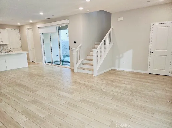 a view of an empty room with wooden floor and staircase
