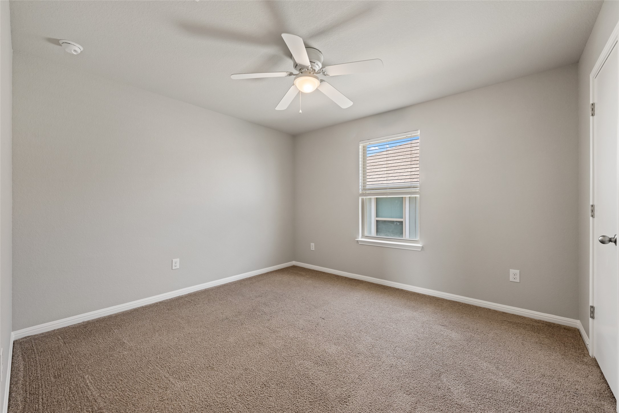 124 Guemal Road Buda, TX 78610 - Photo 27 of 40 A well-lit bedroom features plush carpeting and a ceiling fan for comfort.