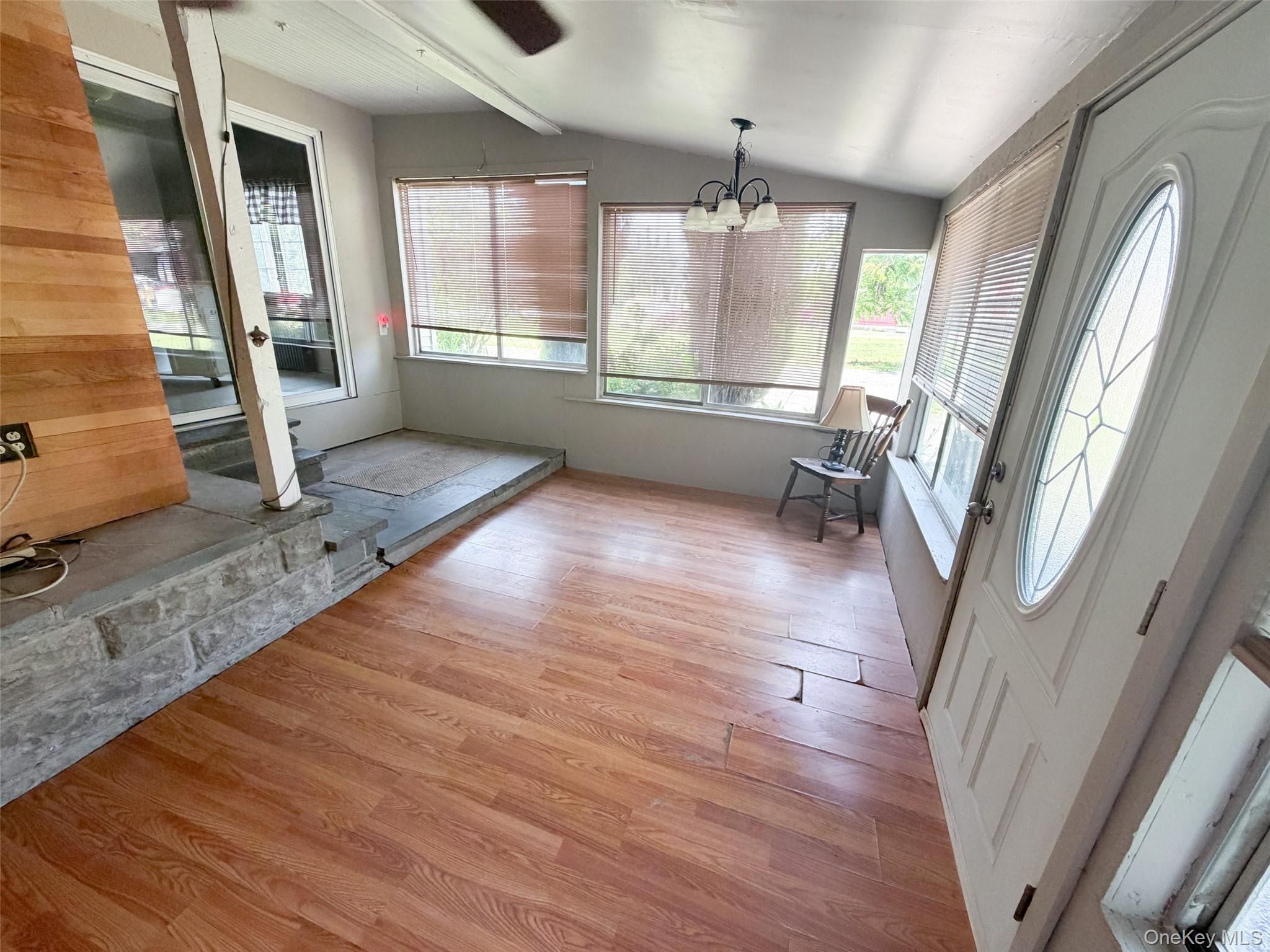 77 Rockland Road Roscoe, NY 12776 - Photo 8 of 20 Sunroom featuring wood-finish flooring, multiple windows with blinds, and a decorative glass entry door