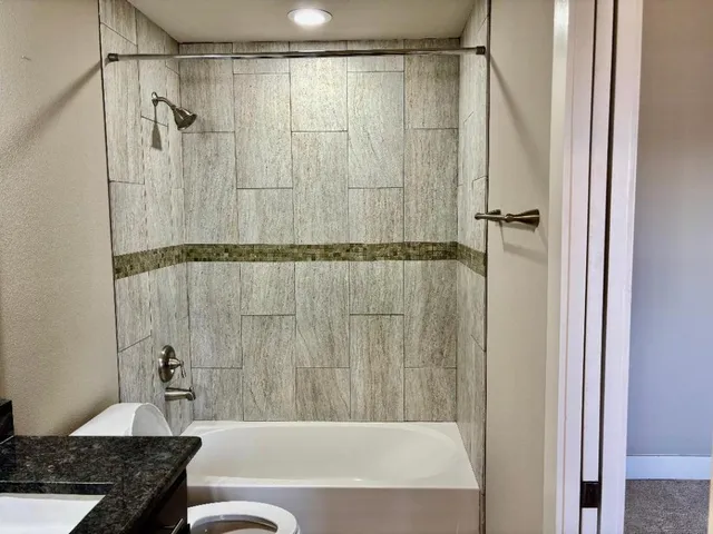a bathroom with a granite countertop bathtub shower and a sink