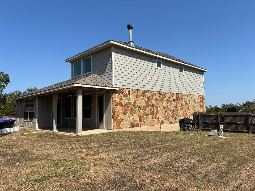 Undisclosed Address Dripping Springs, TX 78620 - Photo 16 of 19 Rear view of property featuring a lawn, a patio, stone siding, and board and batten siding