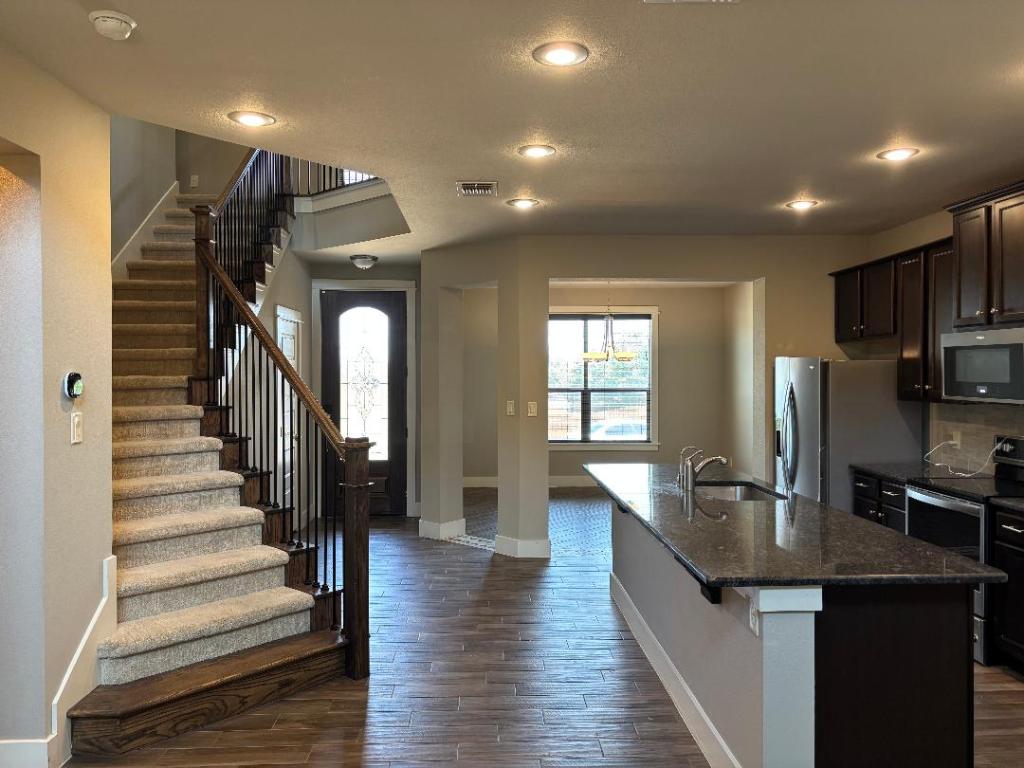 Undisclosed Address Dripping Springs, TX 78620 - Photo 3 of 19 Kitchen featuring stainless steel appliances, granite countertops, tile wood-style flooring, backsplash, and a center island with sink
