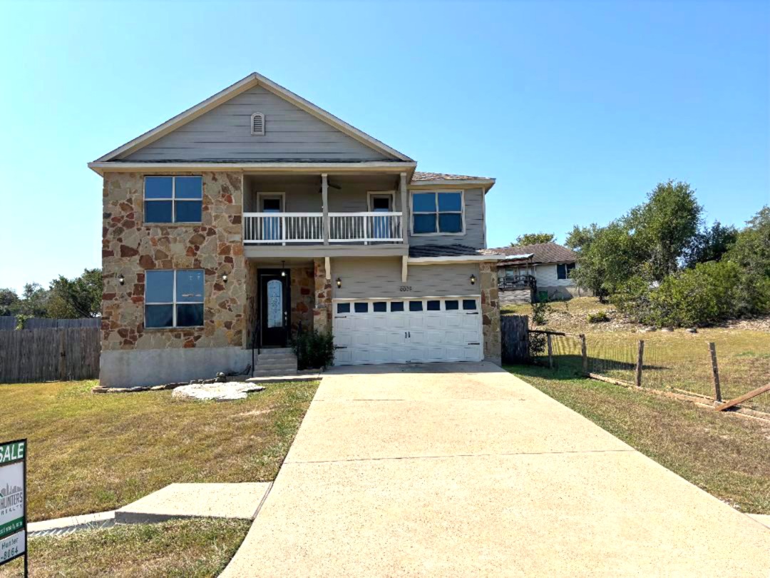 Undisclosed Address Dripping Springs, TX 78620 - Photo 4 of 19 View of front of home featuring stone siding, driveway, a balcony, and a garage