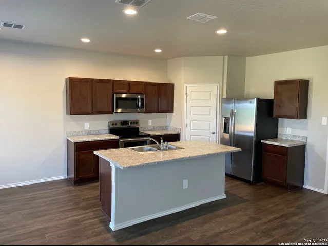 a kitchen with stainless steel appliances a stove top oven a sink a refrigerator and a microwave