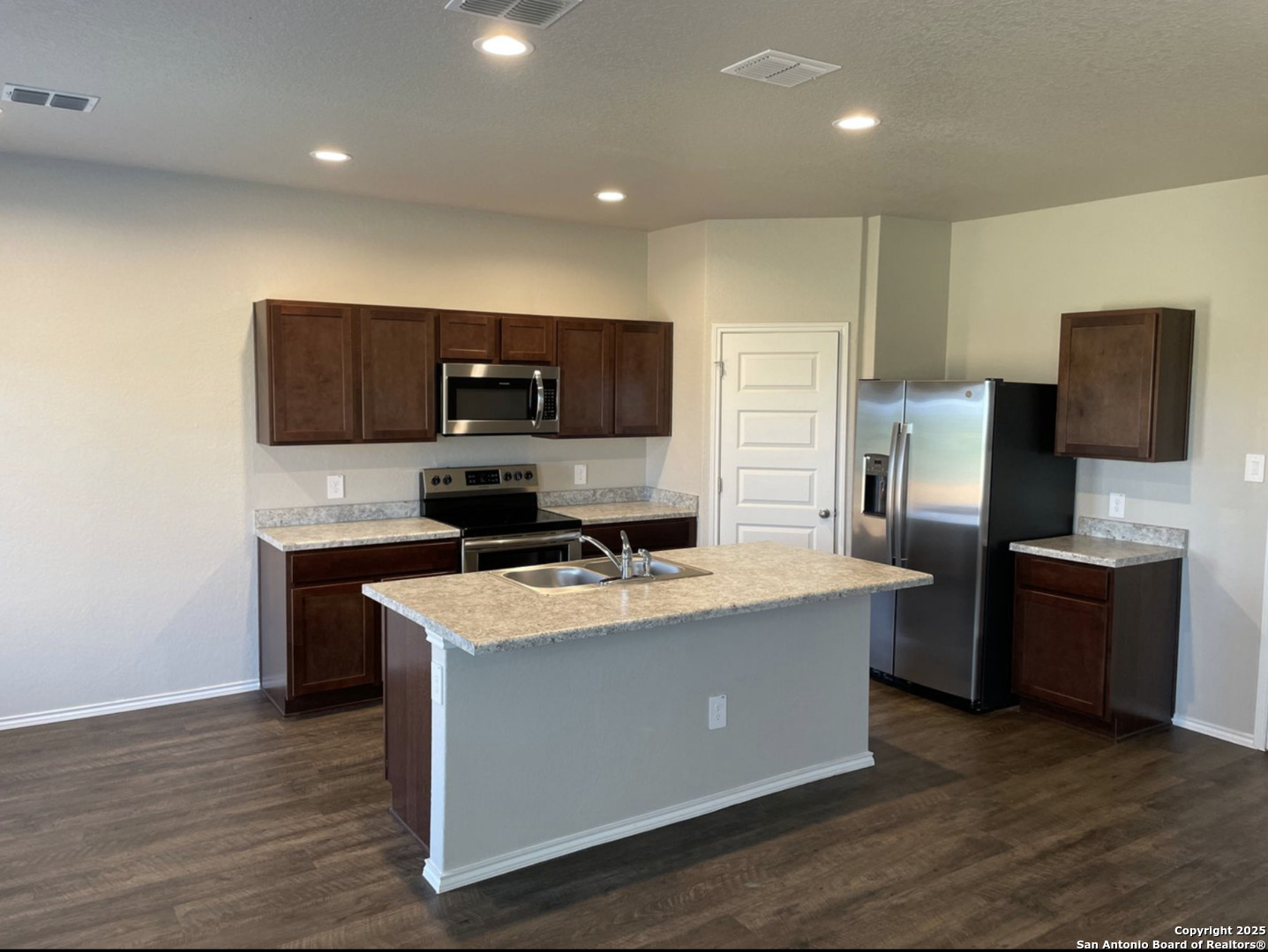 13128 Candace Way St. Hedwig, TX 78152 - Photo 2 of 14 a kitchen with stainless steel appliances a stove top oven a sink a refrigerator and a microwave