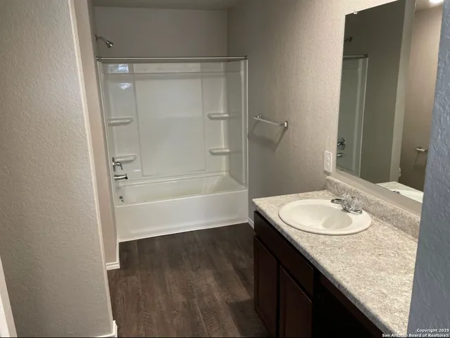 a bathroom with a granite countertop sink a mirror and a bathtub