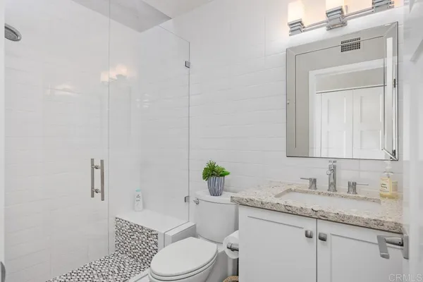 a bathroom with a granite countertop toilet sink and mirror