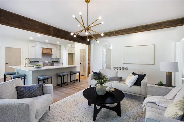 a living room with furniture kitchen view and a chandelier