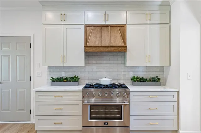 a kitchen with white cabinets and a stove with wooden floor