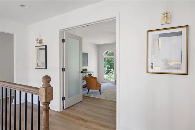 a view of a hallway with couches and a livingroom with wooden floor