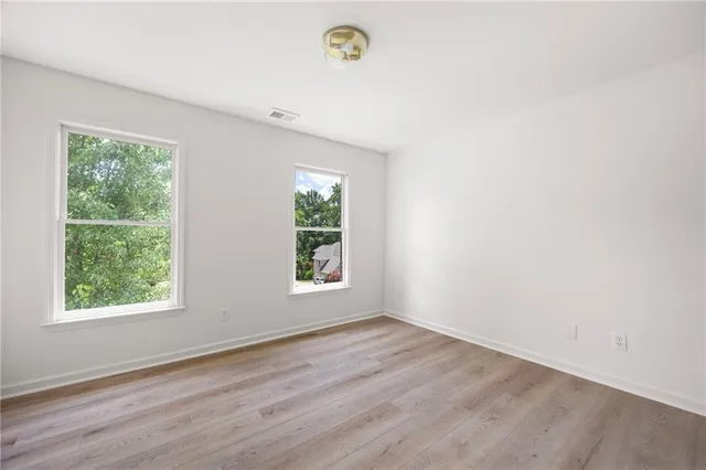 an empty room with wooden floor and window
