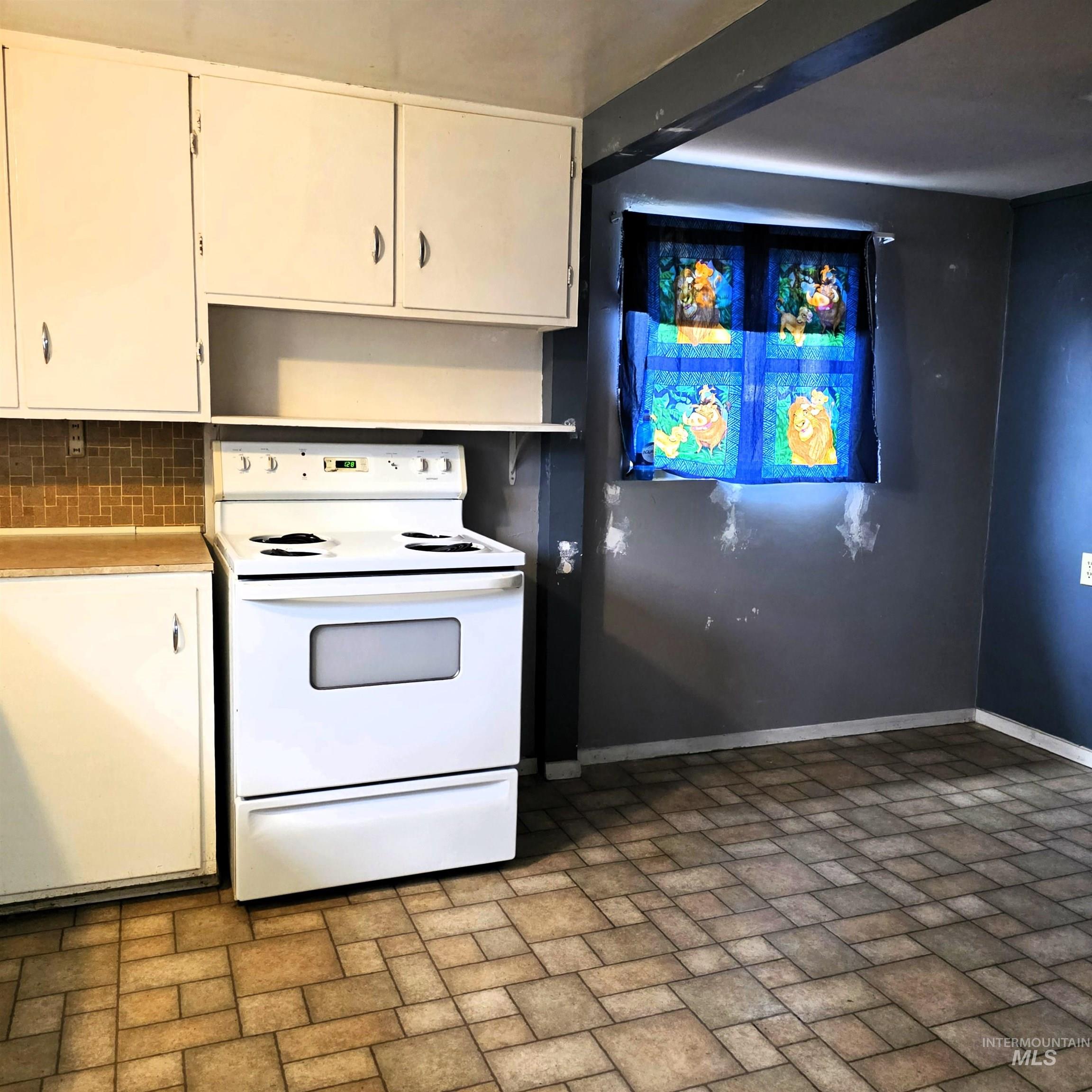 935 Preston Avenue Lewiston, ID 83501 - Photo 7 of 22 Kitchen featuring electric range, white cabinets, brick patterned flooring, light countertops, and decorative backsplash