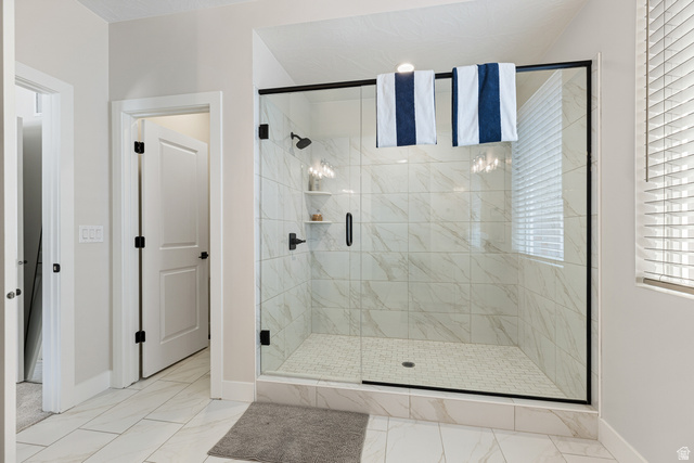 839 Walker Way St. George, UT 84770 - Photo 14 of 32 Walk-in shower featuring a frameless glass enclosure with matte black hardware, white subway tile walls, built-in shelving, and a mosaic tile floor