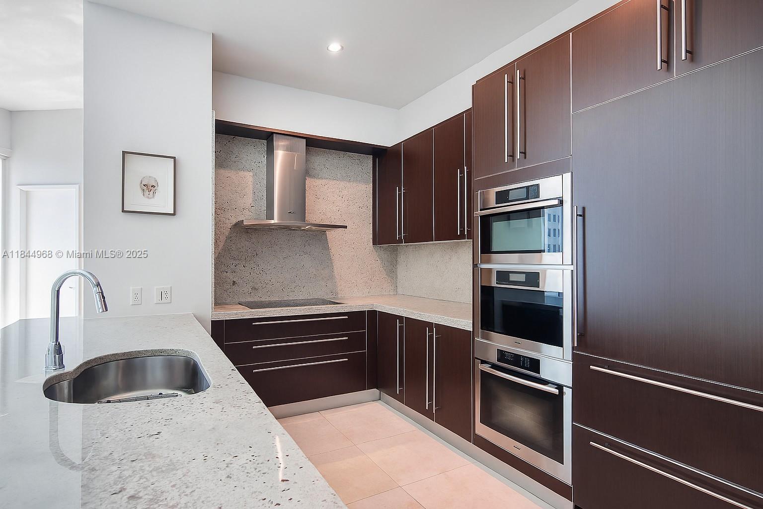 900 Brickell Key Boulevard, Unit 2005 Miami, FL 33131 - Photo 6 of 19 a kitchen with granite countertop a sink and a stove top oven