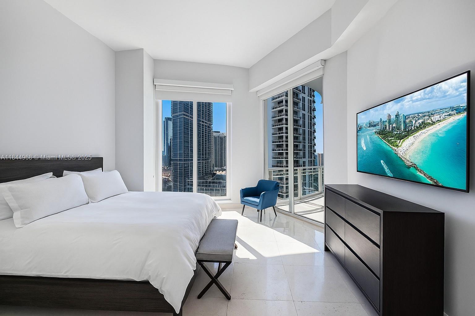 900 Brickell Key Boulevard, Unit 2005 Miami, FL 33131 - Photo 7 of 19 a bedroom with a bed and a flat screen tv