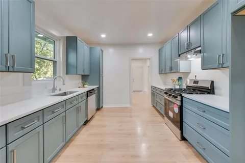 a large kitchen with stainless steel appliances granite countertop a stove a sink and a refrigerator