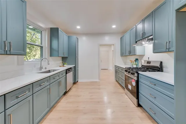 a large kitchen with stainless steel appliances granite countertop a stove a sink and a refrigerator