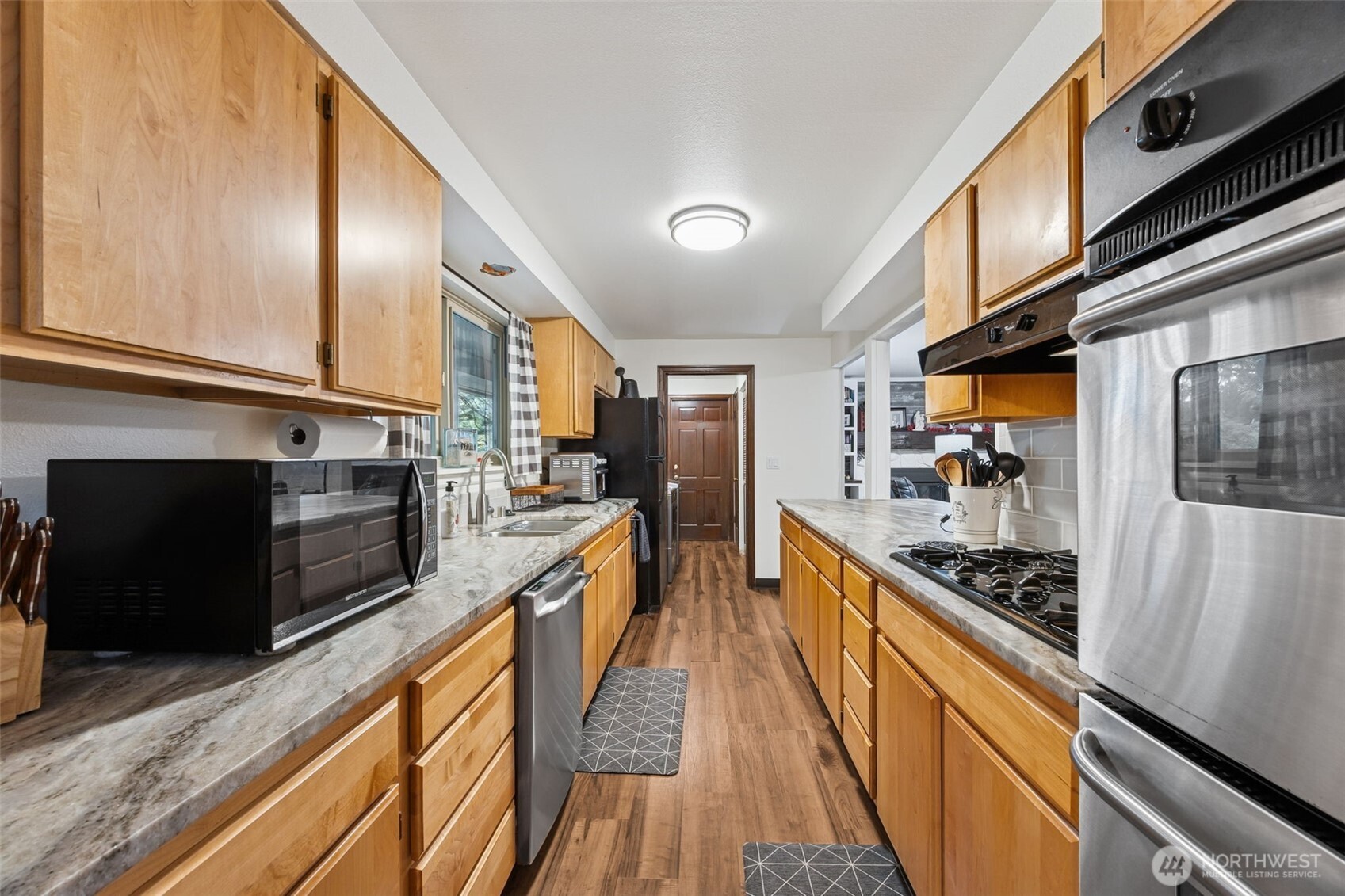 5700 Cooper Point Road Northwest Olympia, WA 98502 - Photo 12 of 31 a large kitchen with stainless steel appliances kitchen island granite countertop a stove a refrigerator a sink dishwasher with wooden cabinets and floor