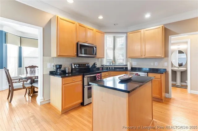 a kitchen with stainless steel appliances granite countertop a stove a sink a microwave a dining table and chairs