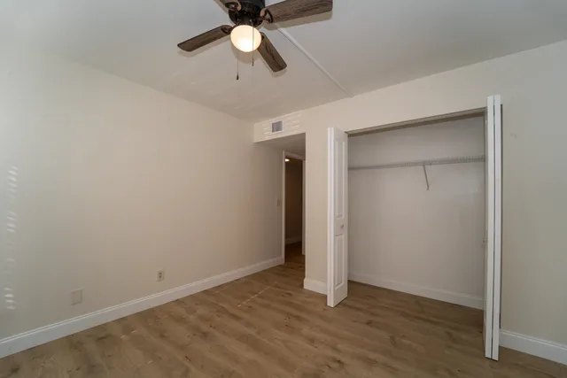 an empty room with wooden floor and ceiling fan