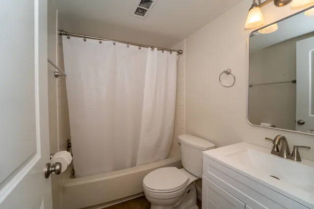 a bathroom with a sink a toilet a mirror and shower curtain