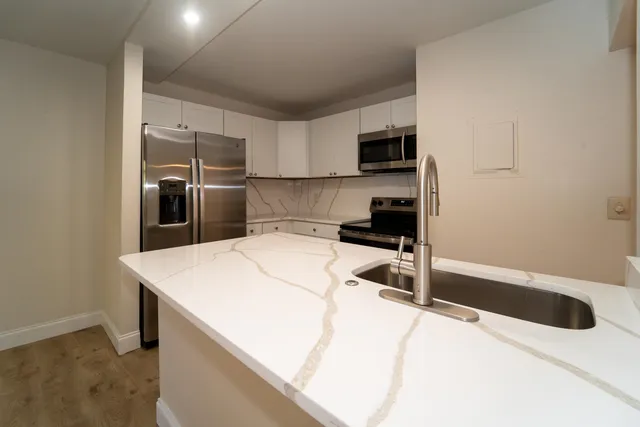 a kitchen with stainless steel appliances kitchen island sink refrigerator and microwave