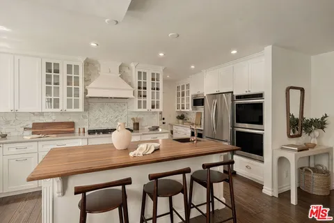 a kitchen with stainless steel appliances a dining table chairs refrigerator and sink