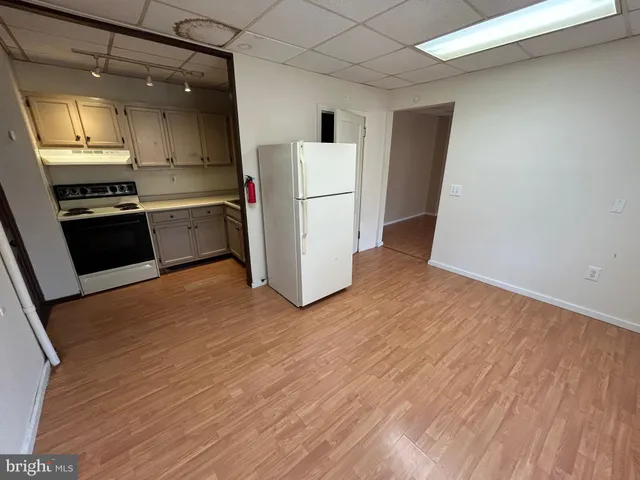 a kitchen with a refrigerator a stove top oven and a wooden floor