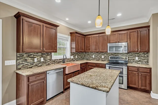 a kitchen with stainless steel appliances granite countertop wooden cabinets a stove a sink and a oven