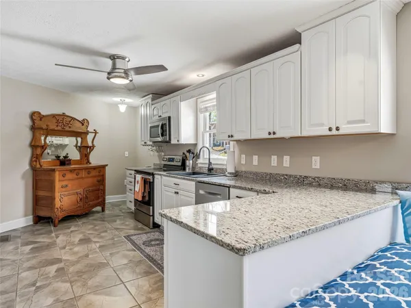 a kitchen with granite countertop a sink a counter top space appliances and cabinets
