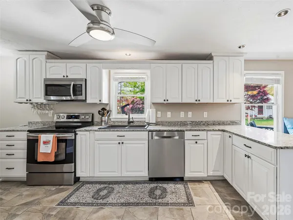 a kitchen with stainless steel appliances granite countertop a stove top oven a sink dishwasher and a microwave oven on the blue kitchen countertops
