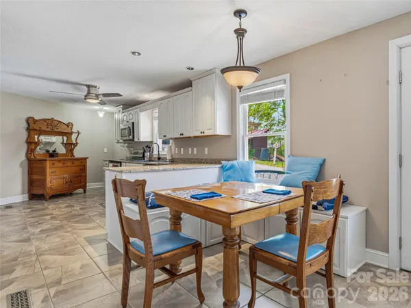 a dining room filled a chandelier and kitchen view