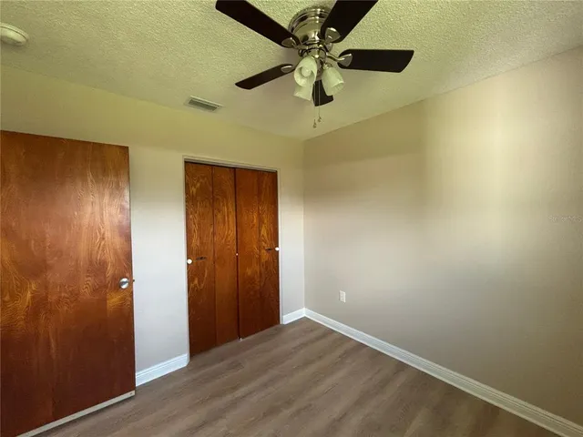an empty room with a ceiling fan and wooden floor