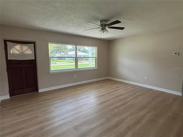 a view of an empty room with wooden floor and a window