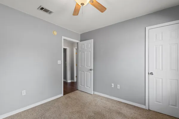 an empty room with windows and chandelier fan