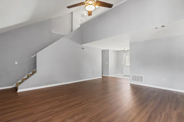 a view of an empty room with wooden floor and a window