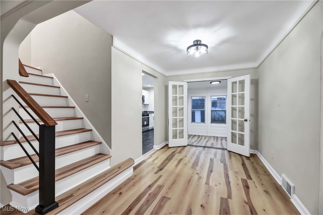 4209 Stilmore Road Cleveland, OH 44121 - Photo 10 of 36 Foyer entrance featuring stairs, french doors, baseboards, visible vents, and wood finished floors