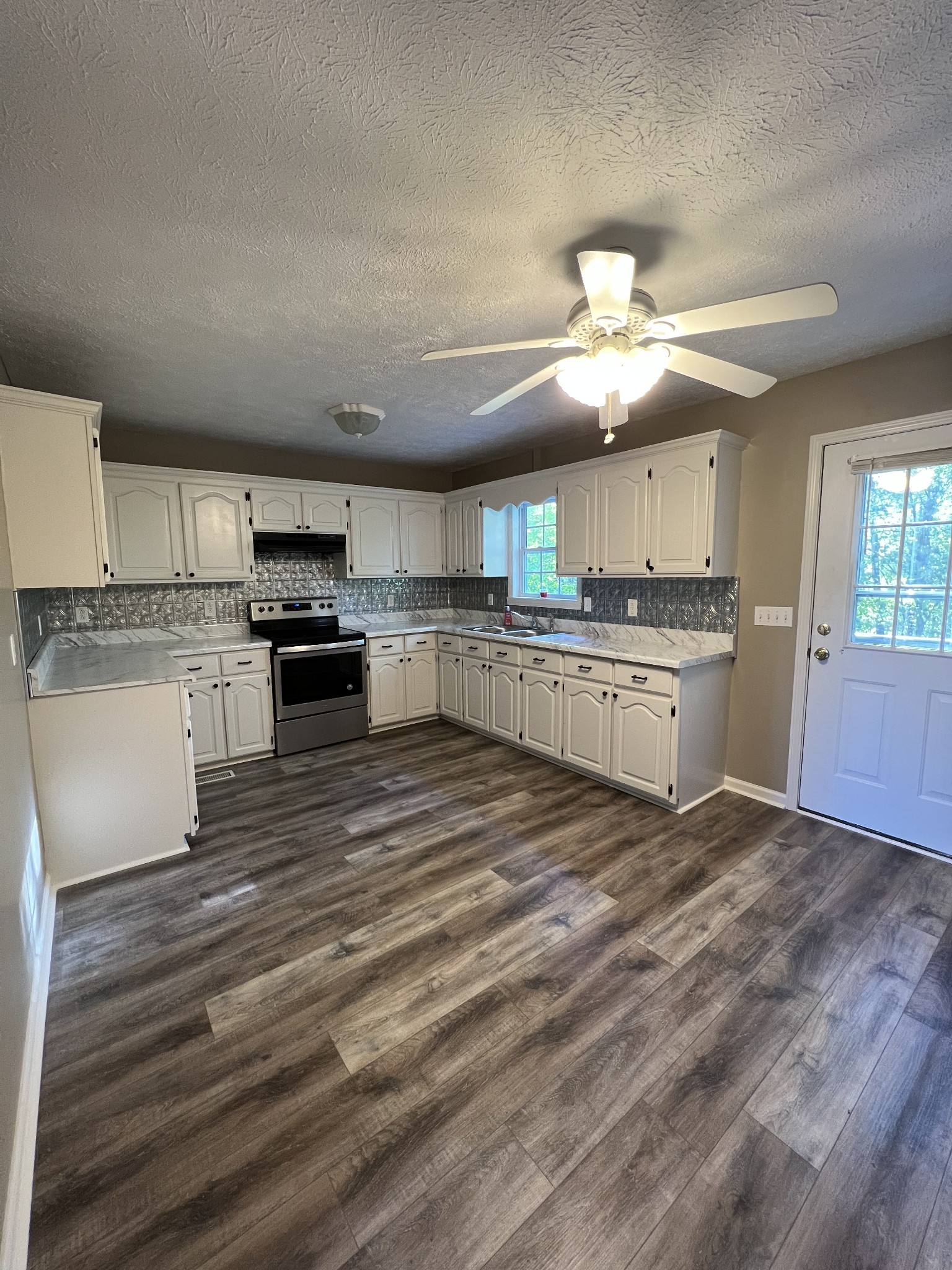 7220 McCormick Ridge Road Whitleyville, TN 38588 - Photo 3 of 9 a kitchen with stainless steel appliances granite countertop a stove top oven a sink dishwasher and a refrigerator with wooden floor
