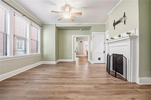 a view of a livingroom with a fireplace a ceiling fan and wooden floor