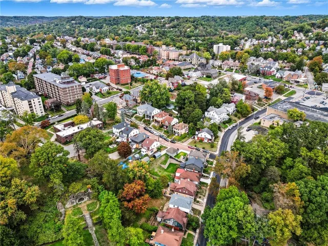 an aerial view of residential houses with outdoor space and trees