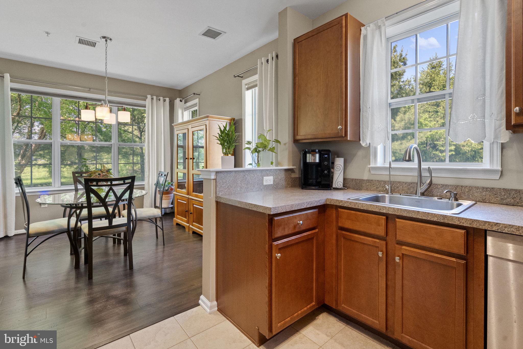 a kitchen with stainless steel appliances granite countertop a stove a sink a dining table and chairs with wooden floor