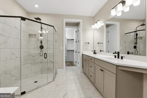 a bathroom with a granite countertop sink two mirror and shower
