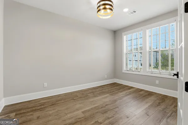 a view of an empty room with a window and wooden floor