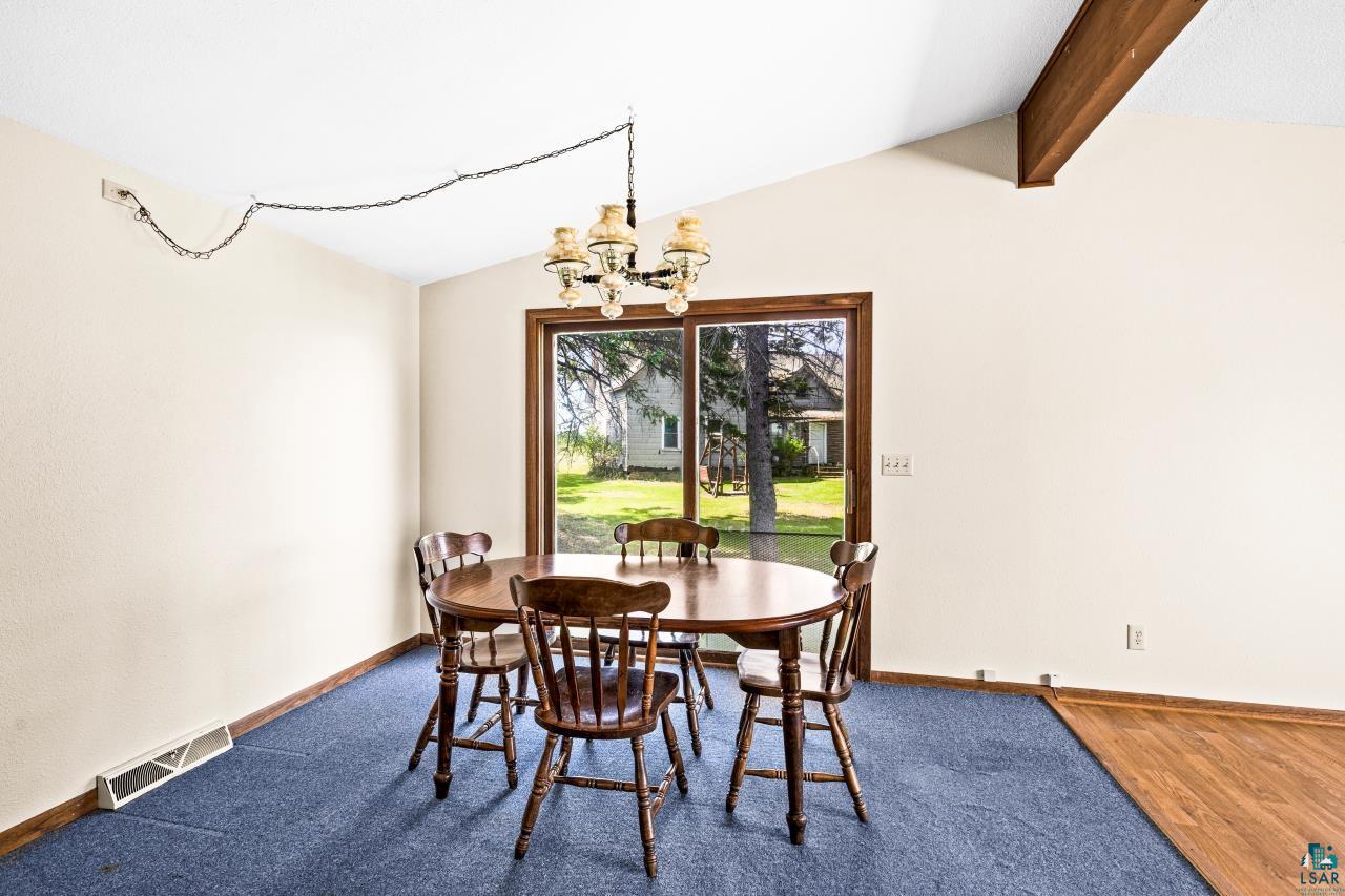 6606 Metso Road Kettle River, MN 55757 - Photo 12 of 84 Dining area featuring a vaulted ceiling with an exposed wood beam, a brass-finish chandelier, and a sliding glass door