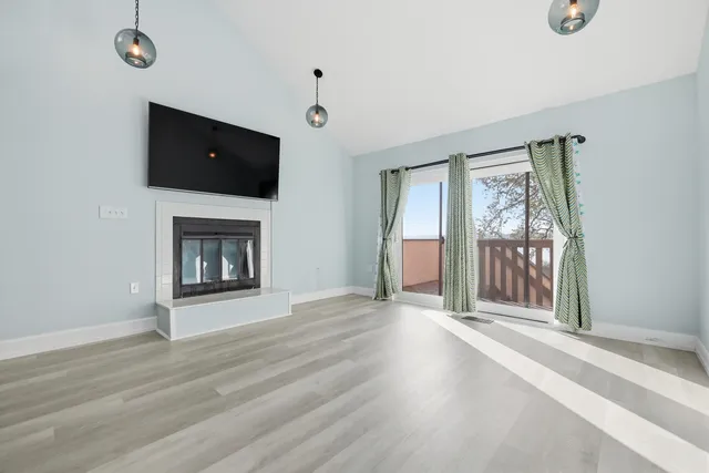 a view of an empty room with wooden floor and windows