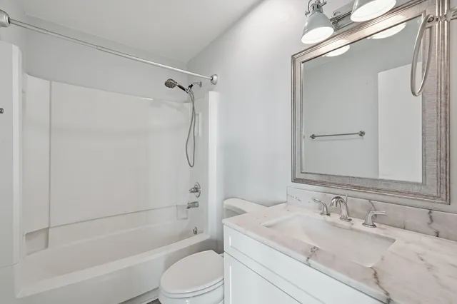 a bathroom with a granite countertop sink a toilet and a mirror