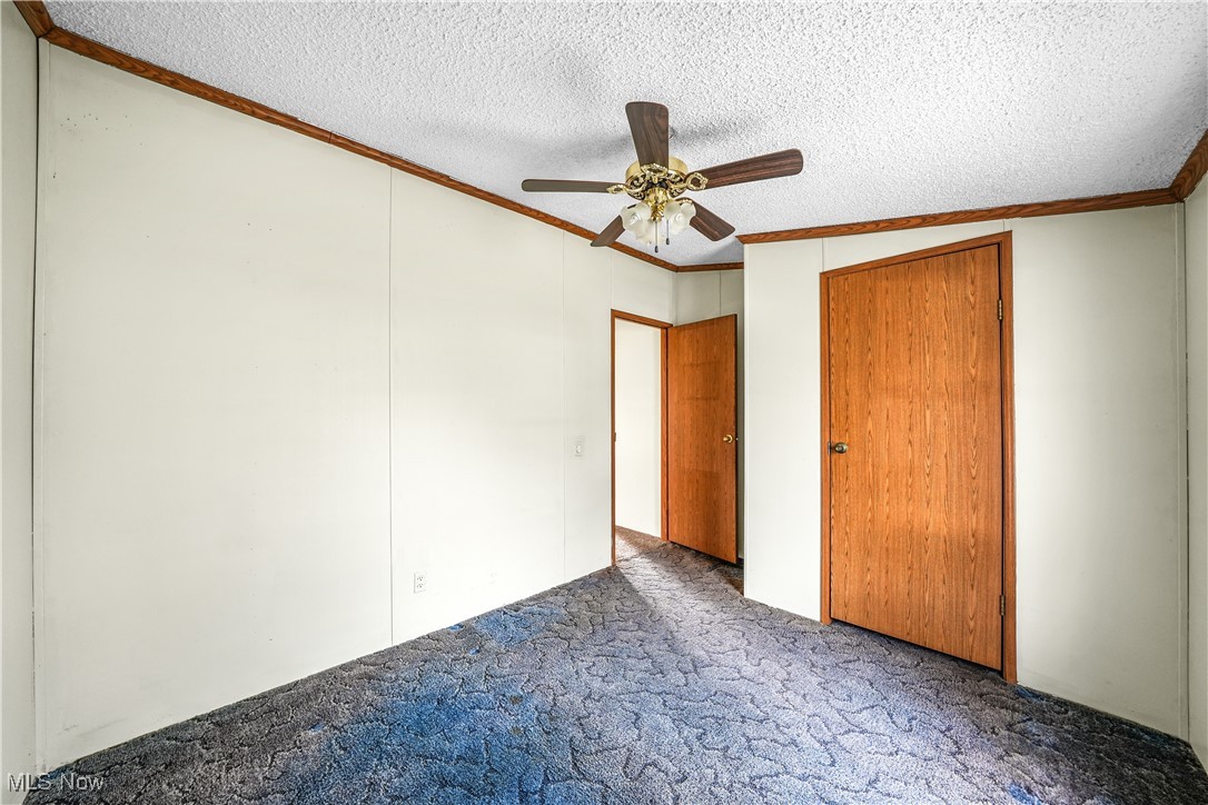3792 Selnik Road Kent, OH 44240 - Photo 21 of 39 Unfurnished bedroom with a textured ceiling, ceiling fan, ornamental molding, a closet, and carpet